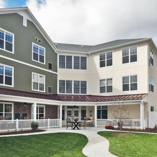 A modern residential building with a well-maintained lawn and pathway.