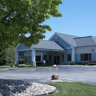 A modern commercial building surrounded by greenery and clear blue skies.