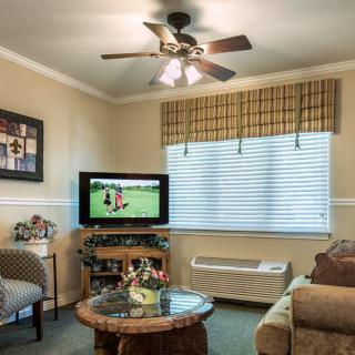 A cozy living room with a television, ceiling fan, and comfortable seating.
