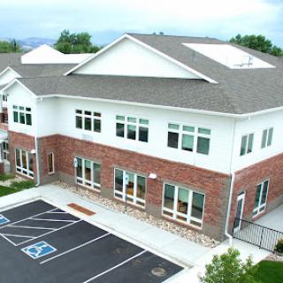 A modern two-story office building with large windows and a spacious parking area.