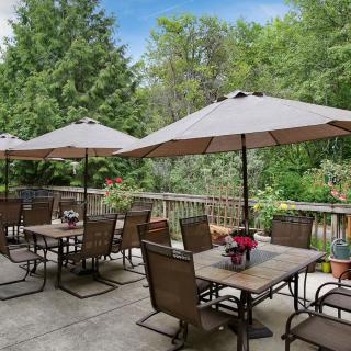 A peaceful outdoor patio with tables and umbrellas surrounded by lush greenery.