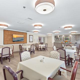 A modern dining room with neatly arranged tables and chairs, featuring elegant lighting and wall art.
