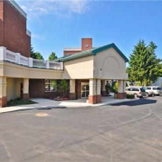A hotel entrance with a covered driveway and adjacent parking area.