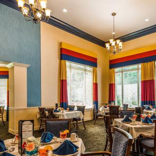 An elegantly decorated dining room with neatly set tables and colorful curtains.