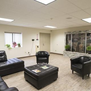 A modern waiting room with black leather seating and a large window.