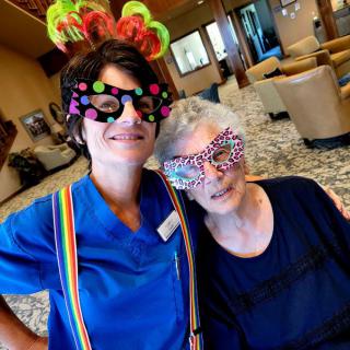 A caregiver and an elderly person enjoying a fun, colorful dress-up moment together.