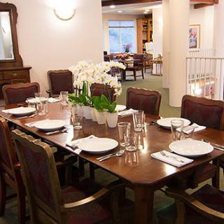 A well-appointed dining room with a large table set for dinner, featuring an orchid centerpiece.