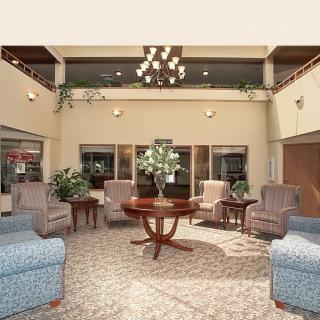 A well-furnished lobby featuring a chandelier, comfortable seating with armchairs, and a central table adorned with flowers.
