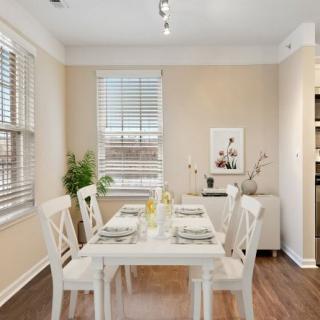 A bright dining room with a white table and chairs, featuring minimalist decor and large windows.