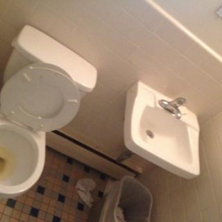A small bathroom featuring a toilet, sink, and tiled floor.