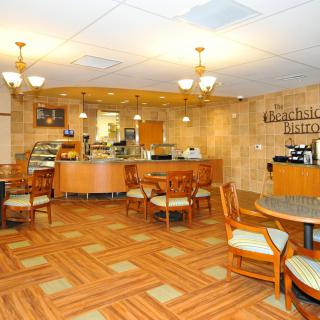 A cozy cafe interior with wooden flooring, seating area, and a counter.