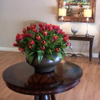 A beautiful arrangement of red tulips in a round vase on a wooden table, enhancing the living room decor.