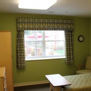 A well-lit hospital room with a bed, window and minimalist furniture.