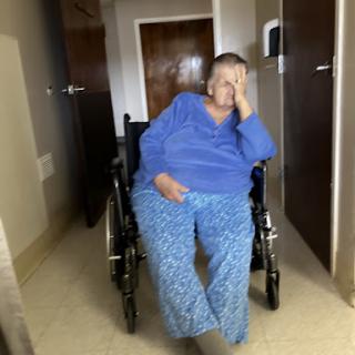 A person sitting in a wheelchair, appearing contemplative or tired in an indoor setting.