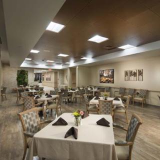 A spacious and elegantly designed restaurant dining area, featuring neatly arranged tables with floral centerpieces.