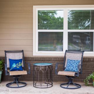 A cozy outdoor patio setup with two chairs, a small table, and decorative cushions.