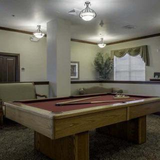 A well-lit game room featuring a shuffleboard table and comfortable seating.