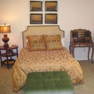 A cozy bedroom with a vintage style, featuring a neatly made bed, decorative pillows, and a classic writing desk.