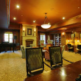 A cozy and elegant office space with brown tones, featuring a fireplace and comfortable seating.