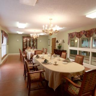A spacious and elegantly arranged dining room, featuring a large table set for a meal.