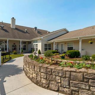 A residential building with a landscaped garden and stone wall under a clear, sunny sky.
