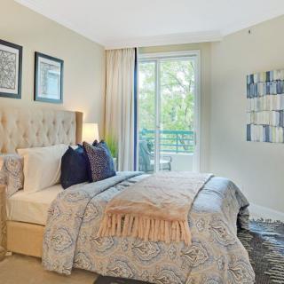 A well-decorated bedroom with a comfortable bed, elegant decor, and natural light from a large window.