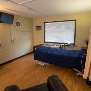 A hospital room with a bed, television, and medical equipment.