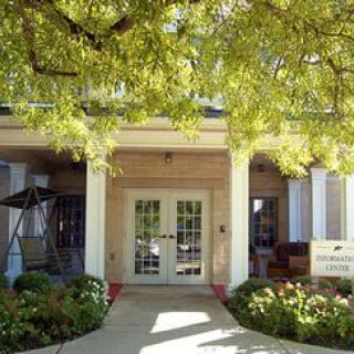 A welcoming building entrance with a porch and surrounding trees.