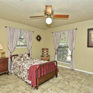 A cozy bedroom with a single bed, ceiling fan, and patterned curtains over the windows.