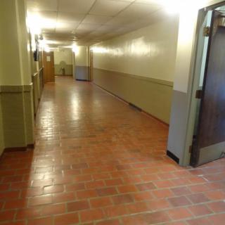 An empty hallway with a brick floor and warm lighting.