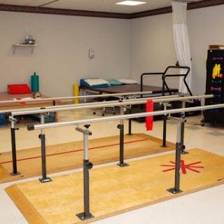 A well-equipped physical therapy room featuring parallel bars for rehabilitation exercises.
