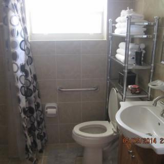 A small bathroom with a toilet, sink, shower curtain, and shelves stocked with towels.