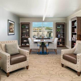 A stylish office interior featuring comfortable chairs, a desk, and bookshelves with decorative items.
