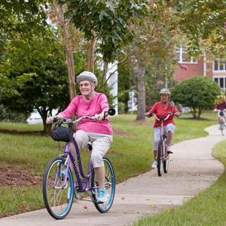 Seniors enjoying a bike ride on a park path.