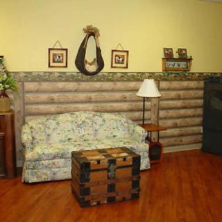 A cozy living room with rustic decor, featuring a floral couch, wooden chest, and floor lamp.