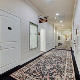 A carpeted hallway with several doors and overhead lighting.