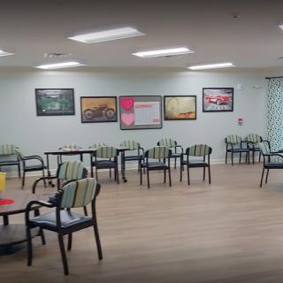 A spacious and well-lit waiting area with chairs and tables, adorned with artwork on the walls.