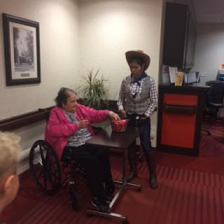 A young cowboy interacts with an elderly woman in a wheelchair during a fun activity.