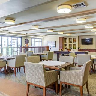 A spacious dining area with tables and chairs, featuring large windows and a television.