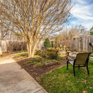 A tranquil garden area featuring a bench, pathway, and trees surrounded by a wooden fence.