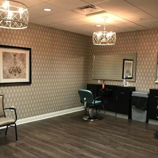 A modern salon interior with patterned wallpaper, mirrors, and elegant chandeliers.