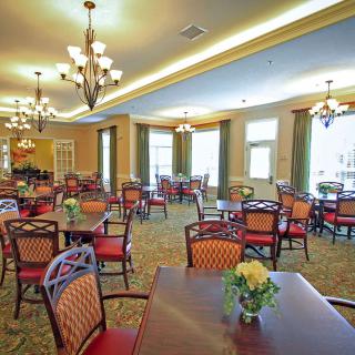 An elegant dining room with chandeliers and neatly arranged tables and chairs.
