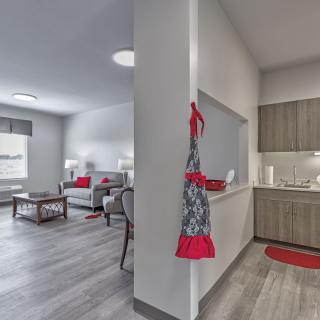 A modern open-plan living room and kitchen with stylish decor, featuring neutral tones and red accents.