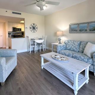 A cozy living room with beach-themed decor, featuring a comfortable sofa and a dining area.