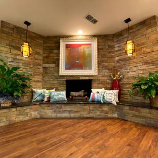 A cozy living room corner featuring a stone wall, decorative lighting, and a welcoming fireplace.