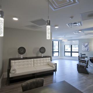 A modern salon interior with stylish lighting, comfortable seating, and workstations equipped with mirrors.
