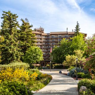 A picturesque view of a modern building surrounded by lush greenery and vibrant flowers, inviting visitors along a winding pathway.