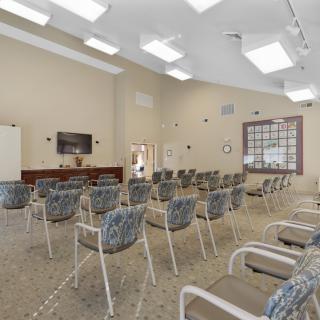 An empty conference room with neatly arranged chairs and a television at the front.
