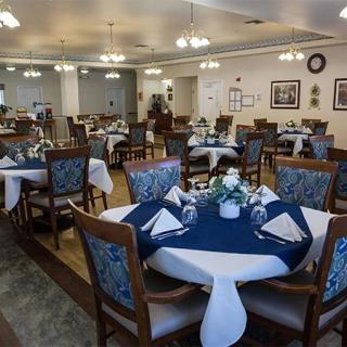A well-arranged dining area with numerous tables set for guests, featuring blue and white tablecloths.