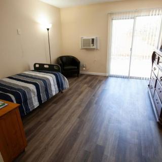 A minimalist bedroom with a single bed, dresser, and chair.